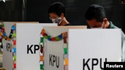 Pemilih yang memakai masker sedang mencoblos surat suara mereka di TPS saat pemilihan kepala daerah di Tangerang, 9 Desember 2020. (Foto: REUTERS/Willy Kurniawan)
