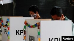 Pemilih mengenakan masker saat menandai surat suara Pilkada mereka di sebuah TPS di Tangerang, 9 Desember 2020. (REUTERS/Willy Kurniawan)
