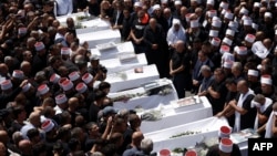 Druze elders and mourners surround the coffins of 10 of the 12 people killed in a rocket strike from Lebanon a day earlier, during a mass funeral in the Druze town of Majdal Shams in the Israel-annexed Golan Heights, July 28, 2024. 