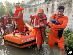 Seorang anggota Pasukan Tanggap Bencana Nasional India (NDRF) menggendong bayi ke tempat yang aman di wilayah negara bagian Himachal Pradesh yang dilanda banjir, Selasa, 15 Agustus 2023. (Foto: NDRF via AP)