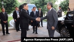 In this photo released by Agence Kampuchea Press (AKP), Chinese Foreign Minister Wang Yi, front right, greets Cambodia's Foreign Minister, SOK Chenda Sophea, front left, in Phnom Penh, April 21, 2024. 