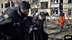 Seorang polisi Ukraina mengevakuasi dua orang lansia yang terluka pasca serangan rudal di kota Kramatorsk pada Selasa, 14 Maret 2023.
