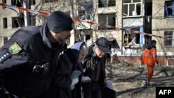 A Ukrainian police officer evacuates an injured elderly woman after a shelling in the town of Kramatorsk on March 14, 2023. 