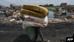 Un homme porte des matelas sur ses épaules près à Marcory Anoumabo, Abidjan, le 23 mars 2024.