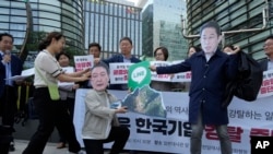 Demonstran Korea Selatan mengenakan topeng dengan wajah PM Jepang Fumio Kishida, kanan, dan Presiden Korea Selatan Yoon Suk Yeol terlihat selama unjuk rasa yang dipicu oleh perselisihan dengan Jepang mengenai aplikasi perpesanan Line, di Seoul.