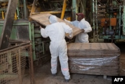Workers load a wooden board used to produce hemp bricks in to a machinery at the Afrimat Hemp brick factory in Cape Town, April 25, 2023.
