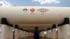 ARCHIVO - Trabajador de la petrolera estatal boliviana YPFB pasa junto a un depósito de gas licuado, El Alto, Bolivia.