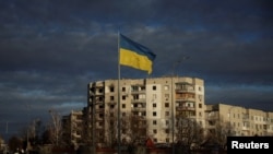 Архівне фото: український прапор поблизу будівлі, зруйнованої ракетним ударом Росії, Бородянка, лютий 2023 року