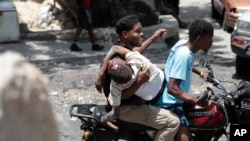 FILE - People take a man who was shot in the head during violent gang clashes to a hospital in the Carrefour-Feuilles district of Port-au-Prince, Haiti, Aug. 15, 2023.