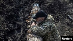 Seorang anggota pasukan Ukraina berdiri di dekat sebuah tank di dekat garis depan pertempuran di Kota Bakhmut, Ukraina, pada 10 April 2023. (Foto: Reuters/Oleksandr Klymenko)