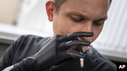 Dr. Alexis Cholas smokes a cigarette using his bionic hand outside of the hospital's rehabilitation center in Kyiv, Ukraine, Nov. 8, 2023.