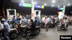 FILE - People wait their turn to get fuel at a petrol station, in Karachi, Pakistan, June 2, 2022.