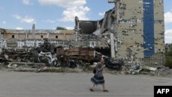 A woman walks past a destroyed building in Mariupol, Ukraine, Aug. 16, 2023, amid the Russian invasion of Ukraine. 