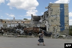 Una mujer pasa frente a un edificio destruido en Mariupol, Ucrania, el 16 de agosto de 2023, en medio de la invasión rusa de Ucrania.