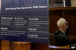 FILE - Sen. David Blount, D-Jackson, right, is reflected against a poster board which outlines how some of the funds were spent in the welfare scandal during a public meeting at the Capitol in Jackson, Mississippi, Oct. 18, 2022.