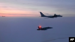FILE - In this March 9, 2020, photo, released by the North American Aerospace Defense Command (NORAD), a Russian Tu-142 maritime reconnaissance aircraft, top right, is trailed near the Alaska coastline.