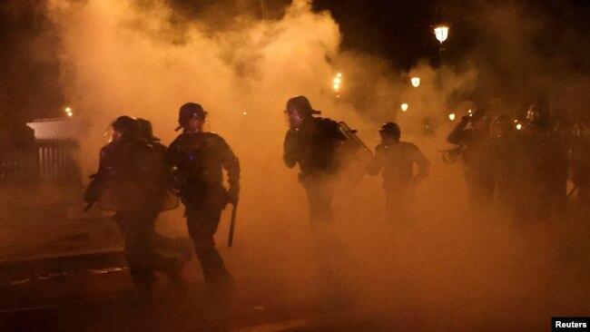 French CRS riot police run amid clashes with protesters during a demonstration as part of the ninth day of nationwide strikes and protests against the French government's pension reform, in Paris, March 23, 2023.