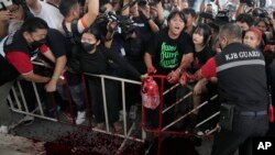 Supporters of Thailand's Move Forward Party, which won the most seats in May's general election, splash a red liquid as they protest their party's exclusion from a coalition that will form the country's next government, in Bangkok, Aug. 2, 2023.