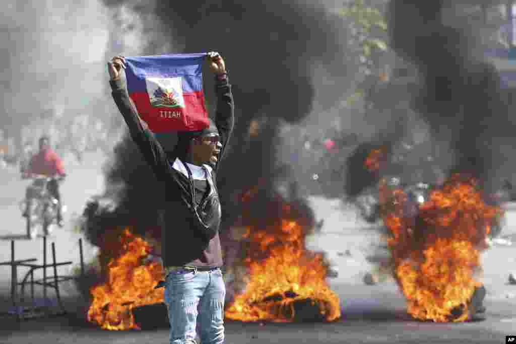 Un manifestante sostiene una bandera haitiana durante las protestas que exigen la renuncia del primer ministro Ariel Henry, quien salió hace más de una semana a una firma de acuerdo de apoyo militar con Kenia, y al regresar se vio impedido de aterrizar en su avión en Puerto Príncipe, Haití, el viernes 1 de marzo de 2024.&nbsp;