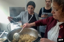 Woman prepare rice for an Easter celebration table set in the garden of the Armenian church Surp Giragos, in Diyarbakir, southeastern Turkey, on April 9, 2023.