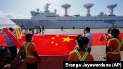 Pekerja pelabuhan Sri Lanka mengibarkan bendera nasional China di Pelabuhan Internasional Hambantota di Hambantota, Sri Lanka, Selasa, 16 Agustus 2022. (Foto: AP)