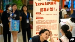 2023年6月9日，一名招聘人員在北京一家購物中心招聘會的展位上與申請人交談。（美聯社照片）
