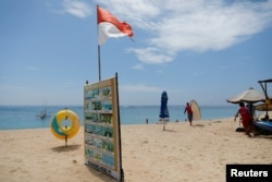 Seorang pria membawa papan selancar di Nusa Dua, Bali, 17 November 2022. (Foto: REUTERS/Willy Kurniawan)