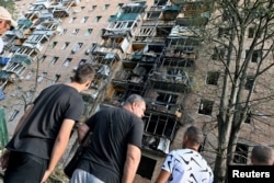 People gather in the courtyard of a residential building, which, according to local authorities, was hit by debris from a destroyed Ukrainian missile, in Kursk, Russia, on Aug. 11, 2024. (Kommersant via Reuters)