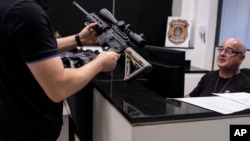 FILE - A gun owner holds a weapon as he registers his firearms with the Federal Police in Rio de Janeiro, Brazil, April 3, 2023.