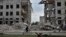 FILE - A local woman rides a bicycle on April 18, 2024, in front of a building destroyed by a Russian airstrike in the frontline town of Orikhiv, Ukraine. 