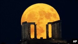 The Blue Supermoon rises behind the Temple of Poseidon at Cape Sounio, south of Athens, Greece.