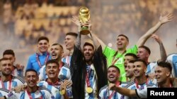 FILE: Lionel Messi mengangkat trofi Piala Dunia dan berfoto bersama rekan satu timnya, merayakan kemenangan Argentina atas Perancis, pada Final Piala Dunia FIFA Qatar 2022 di Stadion Lusail, Qatar, 18 Desember 2022. (REUTERS/Carl Recine)