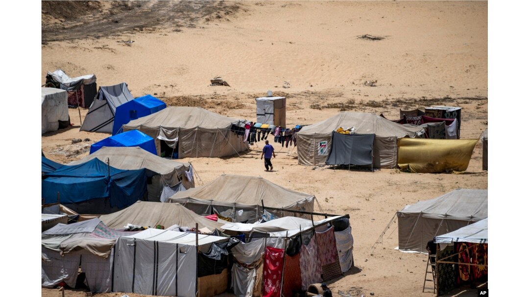 FILE - Seorang pria Palestina yang mengungsi akibat pemboman Israel di Jalur Gaza, berjalan di luar tenda kamp darurat di Khan Younis, Jalur Gaza selatan, 4 Juli 2024. (Abdel Kareem Hana/AP)