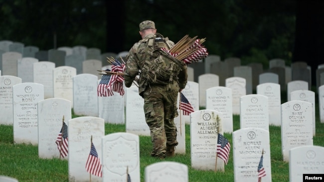 Un soldado de la Vieja Guardia del Ejército de EE. UU. coloca una bandera en una lápida durante el evento anual 'Flags In', antes del Día de los Caídos en el Cementerio Nacional de Arlington en Arlington, Virginia, el 23 de mayo de 2024.