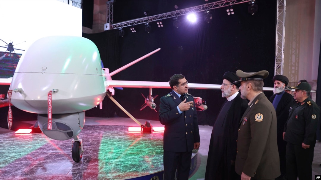 In this photo released by the Iranian Presidency Office, President Ebrahim Raisi (2-L), listens to Chief of Aviation Industries of Iran's Armed Forces Gen. Afshin Khajehfard, as other officials look on, during a ceremony unveiling the Mohajer-10 drone, Aug. 22, 2023.
