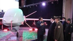 In this photo released by the Iranian Presidency Office, President Ebrahim Raisi (2-L), listens to Chief of Aviation Industries of Iran's Armed Forces Gen. Afshin Khajehfard, as other officials look on, during a ceremony unveiling the Mohajer-10 drone, Aug. 22, 2023.