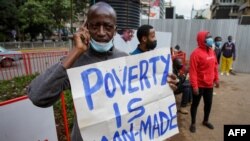 FILE: A protester holds a message "Poverty is man-made" as they demand the Kenyan government take action for better living conditions in the Covid-19 pandemic during a May Day rally marking the international labor day in Nairobi on May 1, 2021 