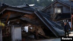 Seorang pria berjalan melewati rumah yang runtuh akibat gempa bumi, di Nanao, prefektur Ishikawa, Jepang 2 Januari 2024. (Foto: REUTERS/Kim Kyung-Hoon)