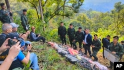 Pj Sekretaris Jenderal Badan Pengawasan Narkotika Phanurat Lukboon (ketiga kanan), berbicara kepada wartawan saat tas berisi pil sabu dipajang di tengah jalan di provinsi Chiang Rai, Thailand, dalam foto yang dirilis 17 Desember 2023. (Kantor Badan Pengawasan Narkoba via AP)
