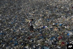 FILE - A boy walks on the plastic waste at the Badhwar Park beach on the Arabian Sea coast in Mumbai, India, June 5, 2023.