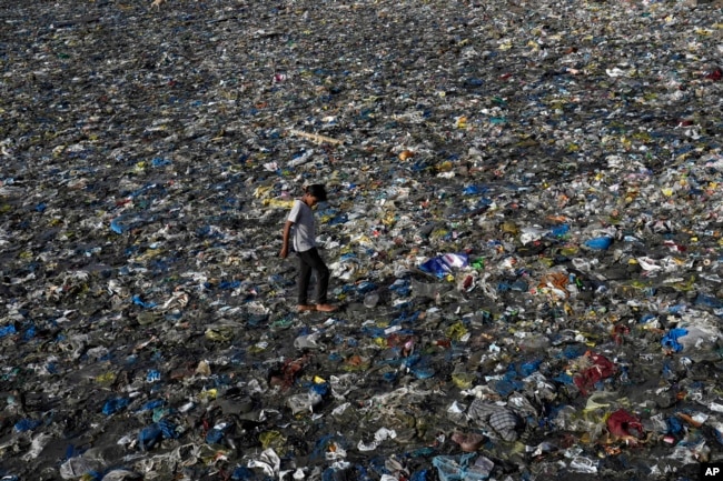 FILE - A boy walks on the plastic waste at the Badhwar Park beach on the Arabian Sea coast in Mumbai, India, June 5, 2023.