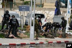 UZNEMIRAVAJUĆI SADRŽAJ - Izraelski policajci stoje pored tela ubijenih militanata, ispred policijske stanice koju su naoružani napadači Hamasa zauzeli dan ranije, u Izraelu, 8. oktobra 2023.