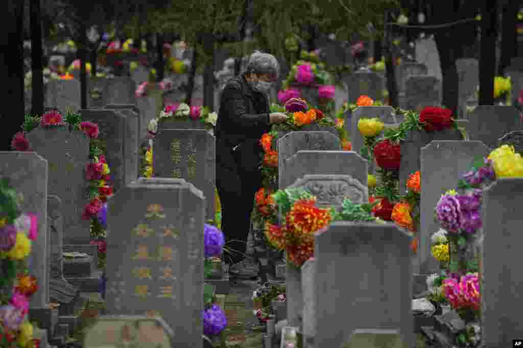 An elderly woman places flowers on a tomb during Qingming festival, also known as Tomb Sweeping Day, when family members visit their ancestral graves to clean up and burn offerings in Beijing.