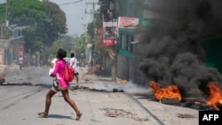 A woman carrying a child runs after gunshots were heard in Port-au-Prince, Haiti, on March 20, 2024. 