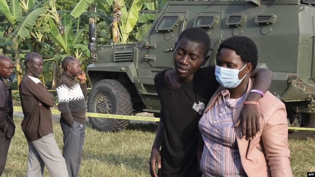 Mwanafunzi asaidiwa na mzazi kwenye shule iliyoshambuliwa na wanamgambo wa ADF huko Mpondwe, Uganda. 