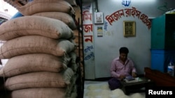 ঢাকার বাবুবাজার শহরের সবচেয়ে বড় পাইকারি বাজারে চালের বস্তার পাশে বসে দোকানের হিসাব করছেন একজন আরতদার। (ফাইল ছবি) 