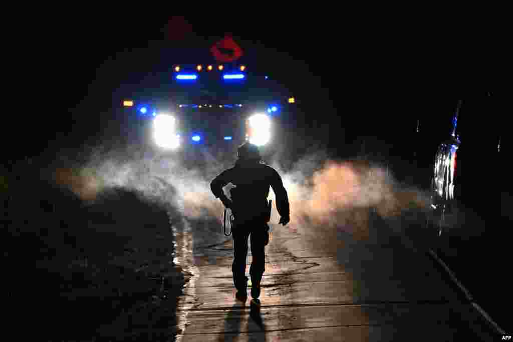 Law enforcement officers are seen outside the home of suspect Robert Card's father and brother in Bowdoin, Maine on Oct. 26, 2023, in the aftermath of a mass shootings in Lewiston, Maine. 