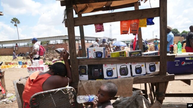 FILE - A woman sells small radio sets at a busy local marketplace stall in Harare, Zimbabwe , Feb. 2, 2023.