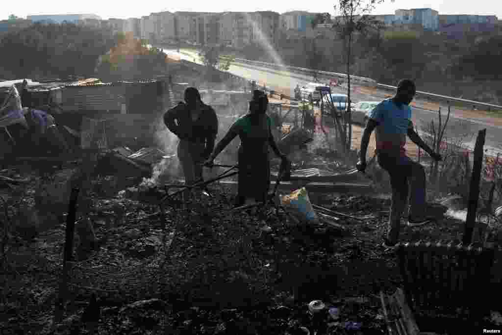 Residents rummage through the remains of their shack after a fire gutted an informal settlement in Fleurof, West of Johannesburg, South Africa, Sept. 3, 2023.