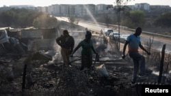 FILE - Residents rummage through the remains of their shack after a fire gutted an informal settlement in Fleurof, West of Johannesburg, South Africa in the early hours of September 3, 2023. 